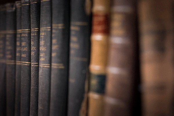 A row of aged books on a bookshelf that have the appearance of legal books.